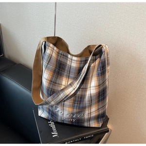 Détail du sac cabas en toile à carreaux avec texte Forever Party sur canapé cuir