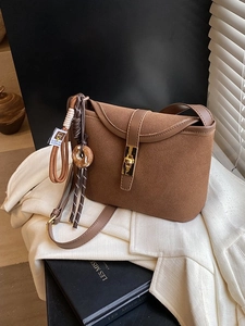 Brown vintage matte suede bucket bag with gold clasp shown on a white blazer