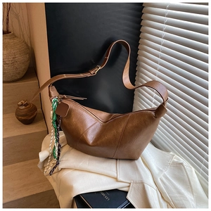 Brown vintage hobo bag on a white blazer with an aesthetic woven charm detail