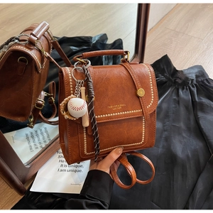 Detailed view of vintage dark brown faux leather mini backpack with baseball keychain