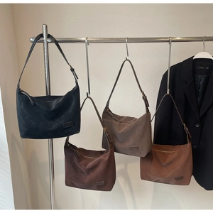 Detail view of suede half-moon bags in four colors with adjustable shoulder straps
