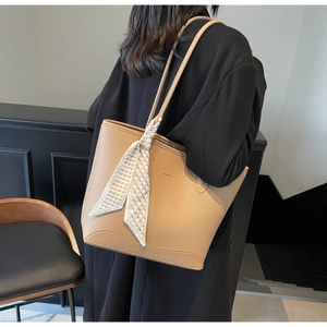 Detail of camel leather tote bag with silk scarf and WHLU logo on a black coat