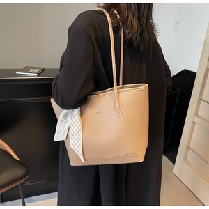 Detail of khaki tote bag with lychee texture and decorative silk scarf on the shoulder strap