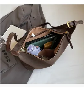 Detail of the spacious interior and adjustable gold buckle of the brown suede tote bag