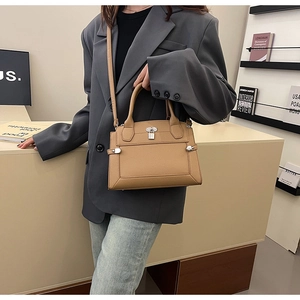 Close-up of khaki pebbled leather handbag with silver lock and dual top handles