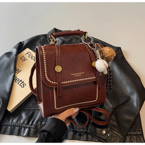 Detailed view of vintage dark brown faux leather bag with baseball and bear charms