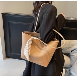 Detail of beige lychee grain leather tote bag with geometric silk scarf on handle