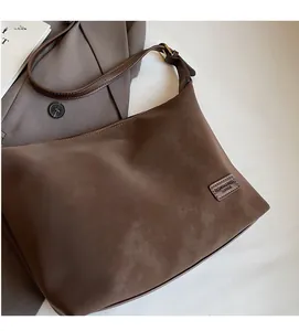 Detail of a brown matte leather tote bag with zipper closure and adjustable strap