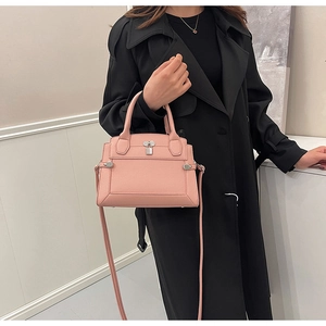 Pink lychee texture handbag with metal padlock detail styled on a black coat