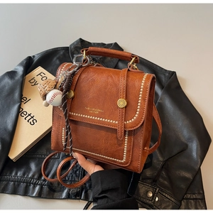 Detail of caramel leather backpack with contrast stitching and baseball charm