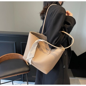 Detail of beige litchi leather tote bag with geometric silk scarf handle and logo