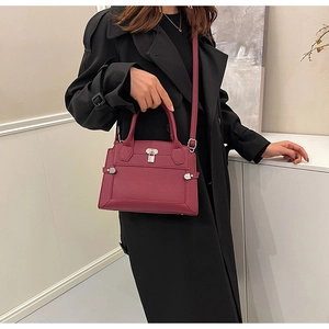 Detail of burgundy leather handbag with litchi texture and elegant metal lock closure