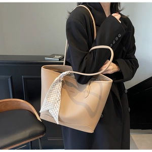 Detail of beige pebble leather tote bag with decorative silk scarf and WWTU branding