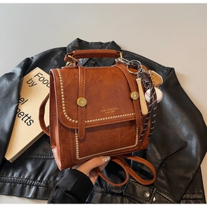 Close-up of vintage brown leather bag with metallic handle and baseball themed charm