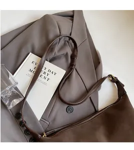 Detail of adjustable long shoulder strap and smooth zipper on brown suede hobo bag
