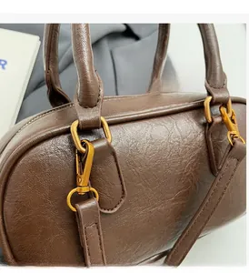 Close-up of litchi texture brown leather on Boston bag with vintage golden hardware