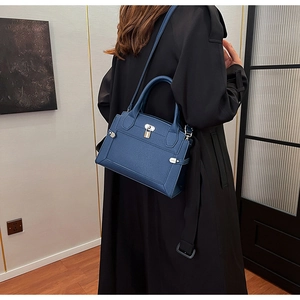 Close-up of dark blue pebble leather handbag with silver lock and shoulder strap