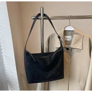Detail of black faux suede hobo bag texture with a minimalist leather logo patch