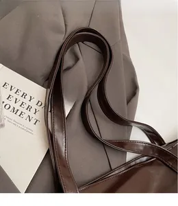 Detail of smooth glossy leather shoulder straps on a dark brown tote bag