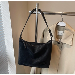 Detail of matte black suede crescent bag showing smooth zipper and adjustable metal buckle