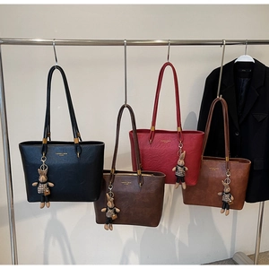 Sacs cabas vintage en quatre couleurs avec breloques lapin suspendus sur un portant
