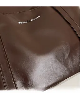 Close-up of dark brown leather tote bag with Believe in Yourself print and fine stitching