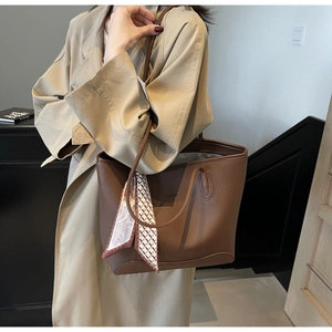 Detail of dark brown pebble leather tote bag featuring a geometric patterned silk scarf