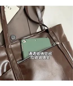 Detail of dark brown tote bag showing the front zipper pocket for mobile storage