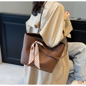 Detail of dark brown pebble leather tote bag with a patterned silk scarf on the strap