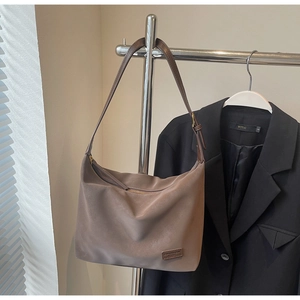 Detail of soft matte coffee hobo bag with top zipper and woven brand tag on corner