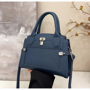 Detail of navy blue pebble leather texture with metallic lock on a high-end handbag