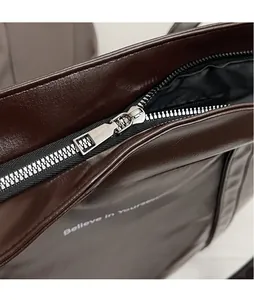 Detail of silver zipper and Believe in yourself print on dark brown leather tote bag
