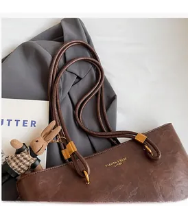 Détail d'un sac cabas marron foncé en similicuir avec anses tubulaires et ferrures dorées