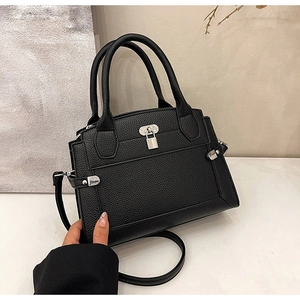 Close-up of black pebble leather tote featuring silver metal lock and detachable strap