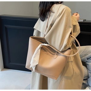 Close-up of khaki pebbled leather tote bag with stylish plaid scarf detail on handle