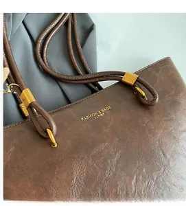 Gros plan du sac fourre-tout en cuir marron vintage avec texture fine et anneaux dorés