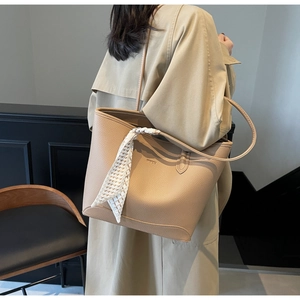Detail showing apricot lychee leather tote bag with silk scarf and logo on shoulder