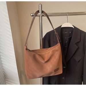 Detail of soft brown matte tote bag with top zipper and fine shoulder strap on display
