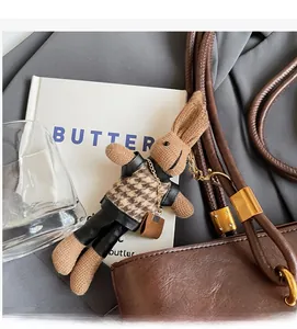 Détail d'un pendentif lapin en peluche avec gilet pied-de-poule marron et mini pochette