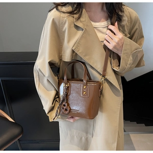 Detail of vintage brown leather bucket bag with gold studs and a round resin charm