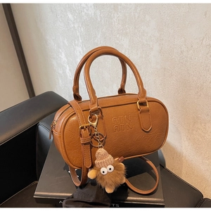 Detail of brown Boston bag with embossed ATN logo and cute plush charm pendant