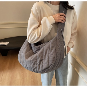 Detail of dark grey quilted nylon tote bag with wide shoulder strap and side drawstring