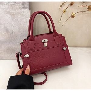 Detail view of burgundy lychee grain leather handbag with silver lock and studs