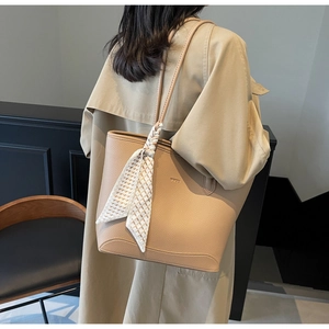 Detail of khaki leather tote bag with embossed logo and decorative silk scarf on strap