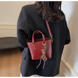 Detail of red leather bucket bag with unique woven rope and gold abacus charm decoration
