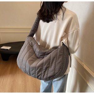 Large gray quilted tote bag on model showing soft puffy texture and spacious design