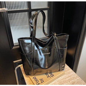 Close-up of black patent leather tote bag with white Believe in Yourself slogan