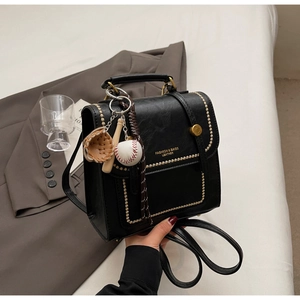 Close-up of black PU leather bag with gold studs and baseball theme decorative charms