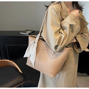 Detail of beige lychee leather tote bag featuring WWTU embossed logo and geometric scarf decor
