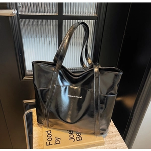 Glossy black tote bag with 'Believe in Yourself' slogan on a minimalist stone shelf